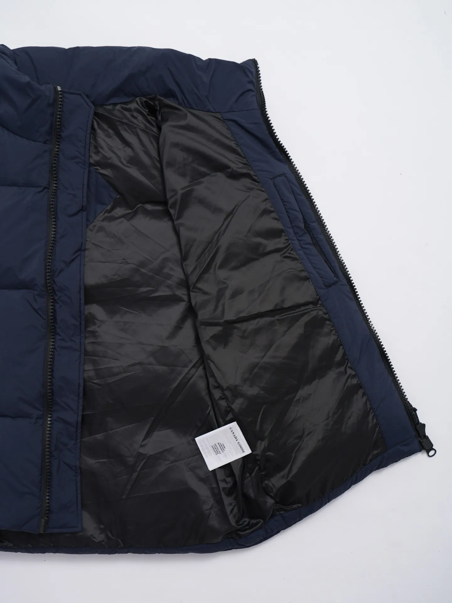 P580 Canada gooes Lawrence Down Vest (high version) With a durable shell and quilted body, the Lawrence Down Vest is a must-have for all seasons. The fabric has a durable soft touch. Longer hem at back for added protection. Reflective double-stripe grip tape at back. The Lawrence features an engineered down-filled collar to block strong winds, a two-way front zip and a longer rear hem. Color: black with red label, black with black label, desert color, ocean blue Size: XS -2XL